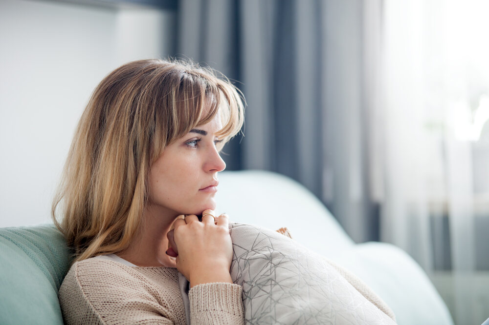 Young woman looking thoughtfully out a window at home
